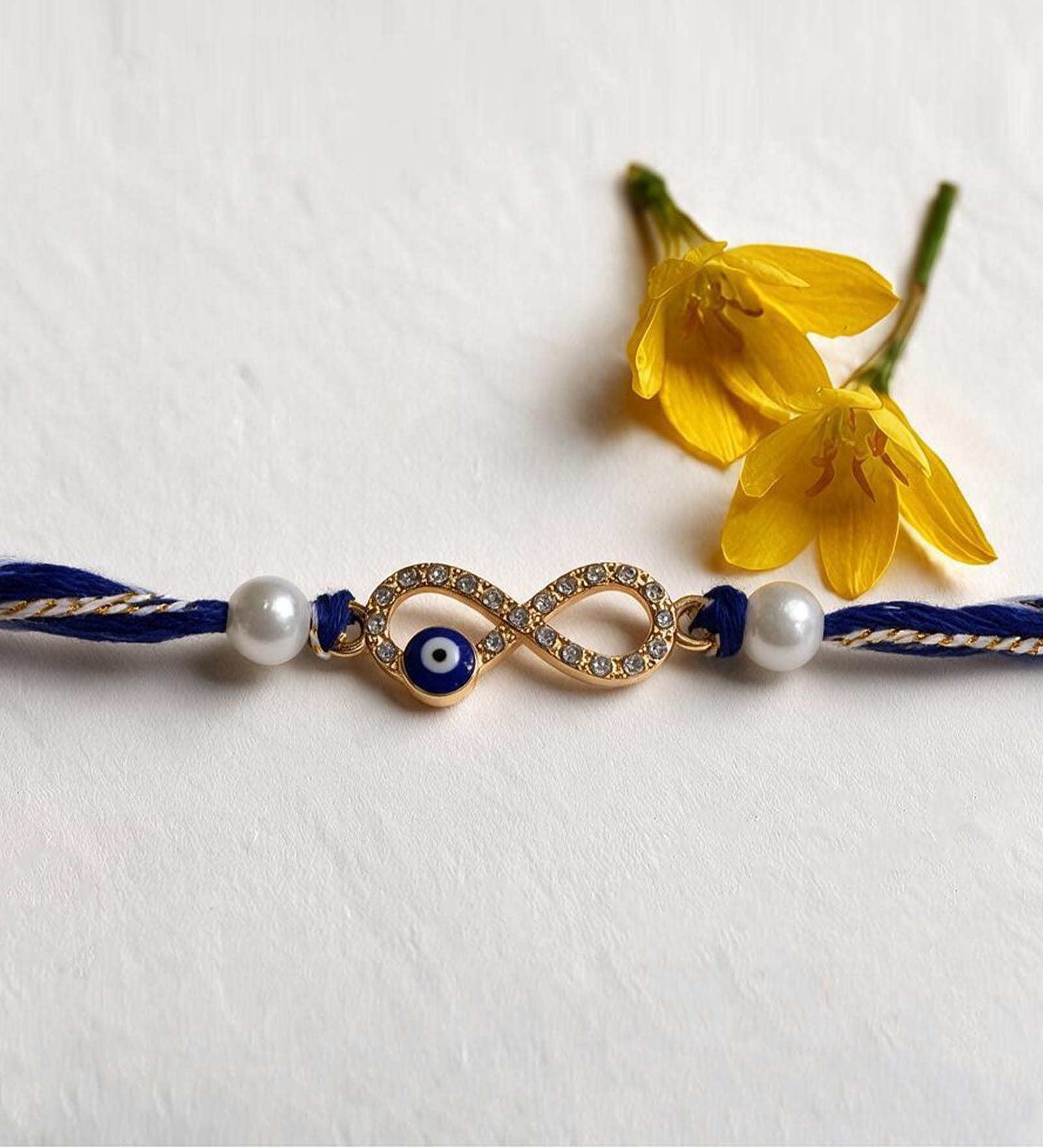 Blue Handmade Infinity Evil Eye Rakhi With Crystal Stones, Pearl Beads & Cotton Thread
